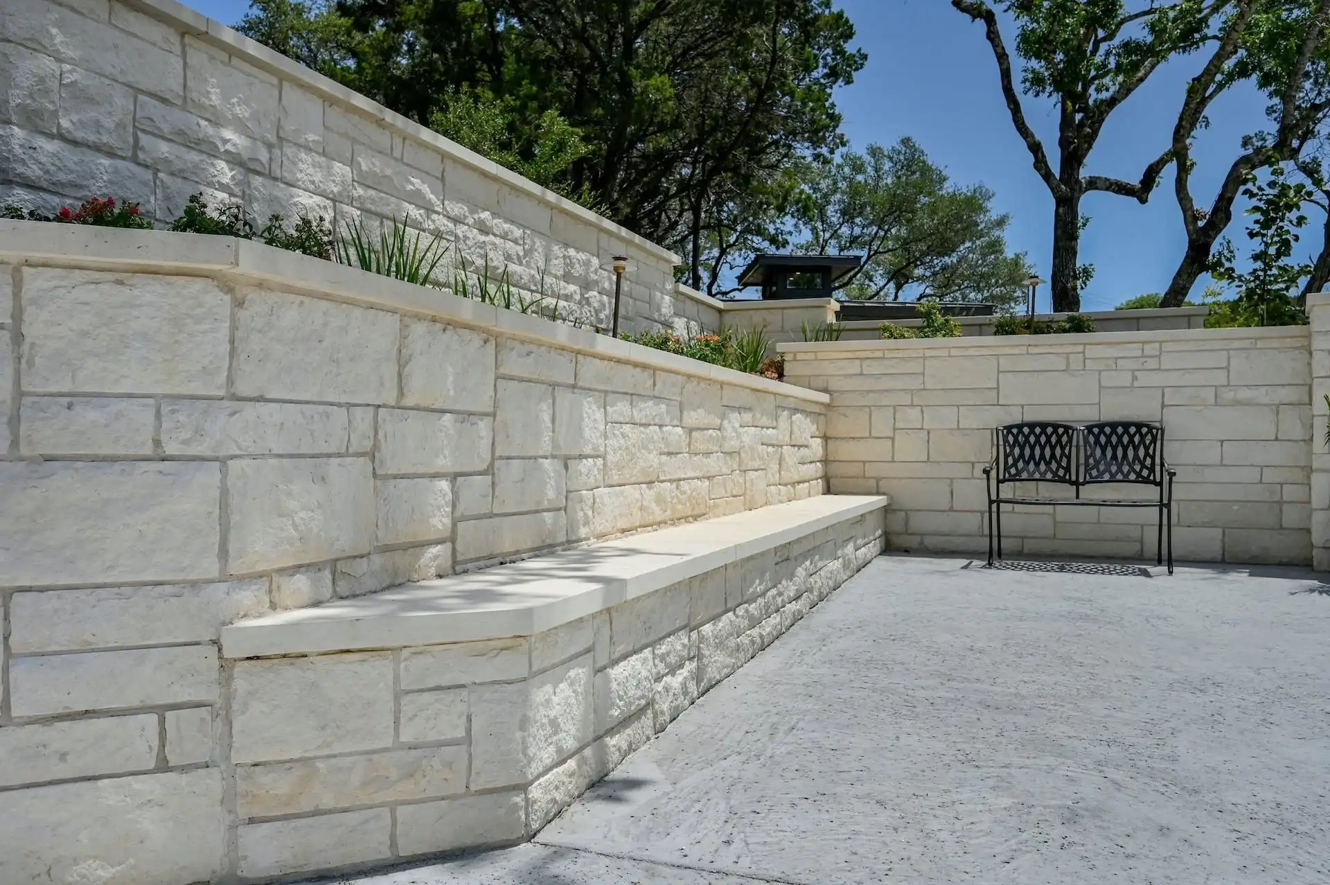 Terraced sawn limestone retaining walls with a built-in seat wall under live oaks