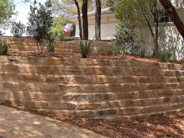 Several stepped block retaining walls terracing a slope beside a house