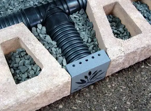 Perforated drain pipe and gravel set behind retaining wall blocks